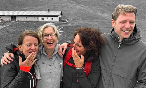 Das Team der vhs Oberhaching bei einem gemeinsamen Ausflug vor der malerischen Sekaralm. Vor alpiner Kulisse zeigt sich das Team in fröhlicher Stimmung – herzlich lachend, nah beieinander und spürbar verbunden. Die Berghütte im Hintergrund und das weitläufige Almgelände unterstreichen das gemeinschaftliche, naturverbundene Erlebnis.