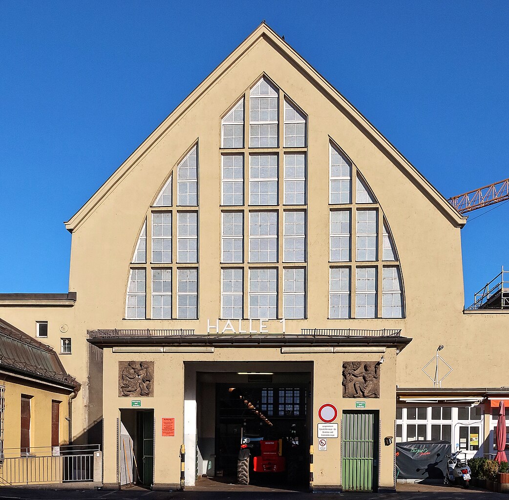 Fassade der Grossmarkthalle in München mit großen Fenstern und einem spitzen Dach.