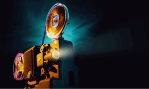 Ein Filmprojektor mit drehenden Spulen und einem Lichtstrahl, der aus dem Objektiv strahlt.
