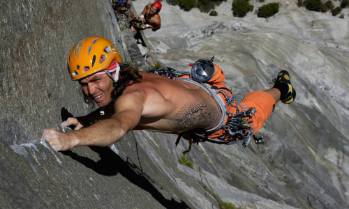 Thomas Huber klettert konzentriert eine steile Felswand hinauf – Symbol für Mut und Leidenschaft im Bergsport