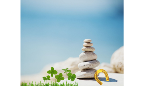 Steinturm und Kleeblätter am Wasser – Symbolbild für Ruhe und Entschleunigung