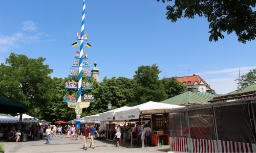 Blick über den Viktualienmarkt in München mit traditionellem Maibaum und belebten Marktständen