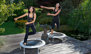 Zwei Frauen trainieren Balance Swing Fitness auf dem Minitrampolin im Freien und führen Gleichgewichtsübungen aus.